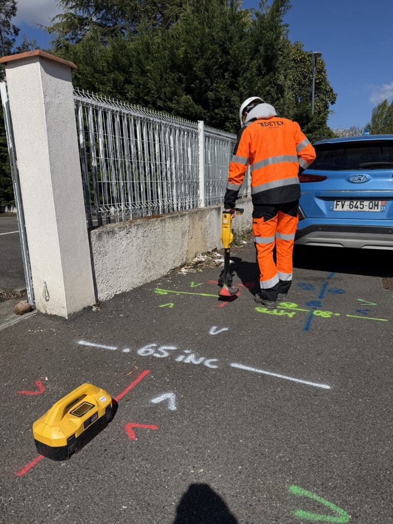 Détection de réseaux enterrés avec technicien RDETEK Technicien RDETEK utilisant un localisateur de réseaux sur marquages au sol avec l'inscription .65 INC.