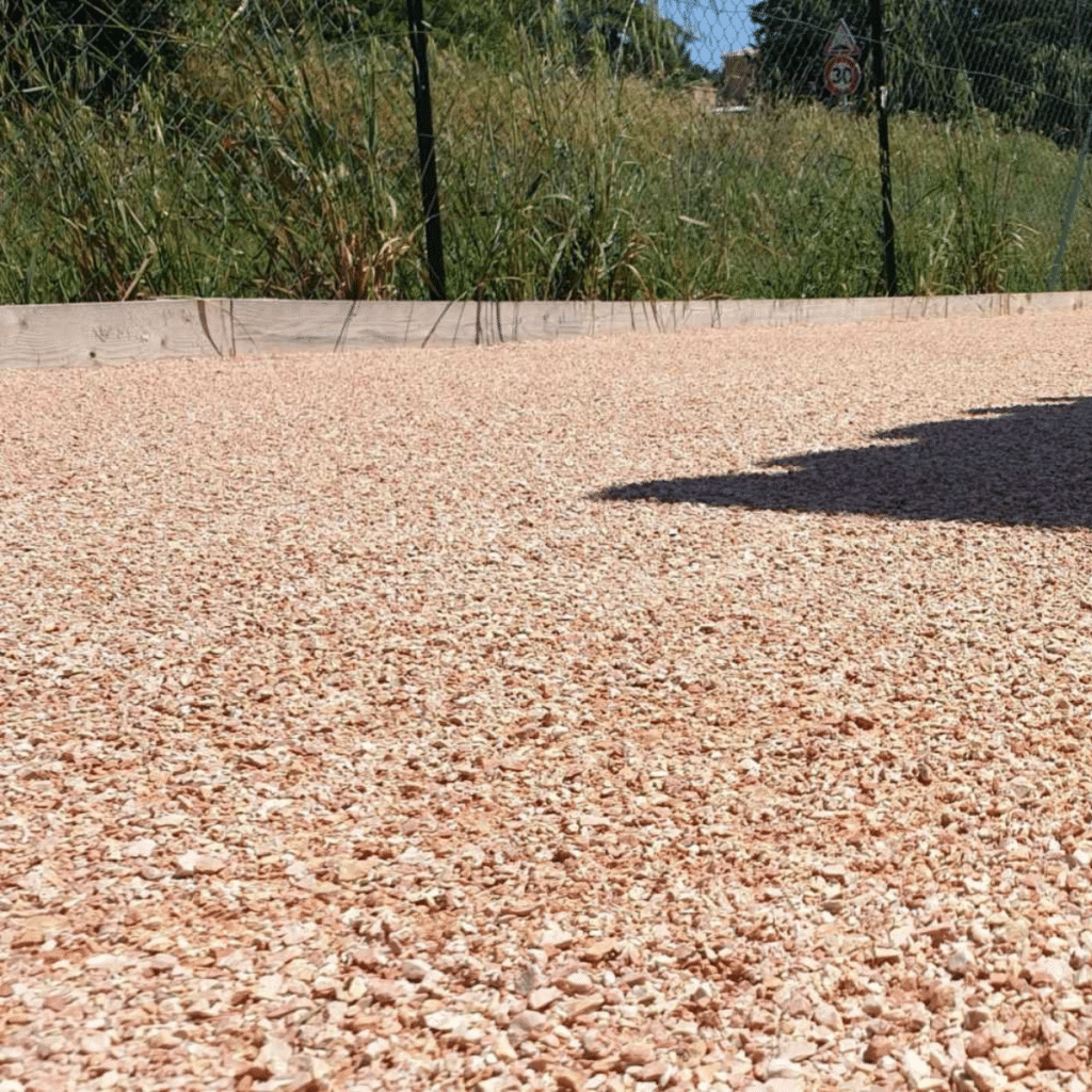 Gravier Rose Concassé : Aménagement Extérieur et Jardin Surface de gravier rose concassé décoratif pour aménagement de jardin avec bordure en bois.