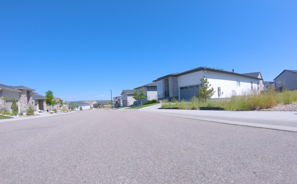 Quartier résidentiel moderne et calme sous ciel bleu Rue résidentielle calme avec maisons modernes, pelouses entretenues et ciel bleu dégagé dans un nouveau quartier.
